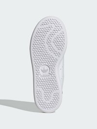 White sneaker outsole featuring hexagonal tread pattern, smooth rubber texture, and embossed Adidas logo at the heel.