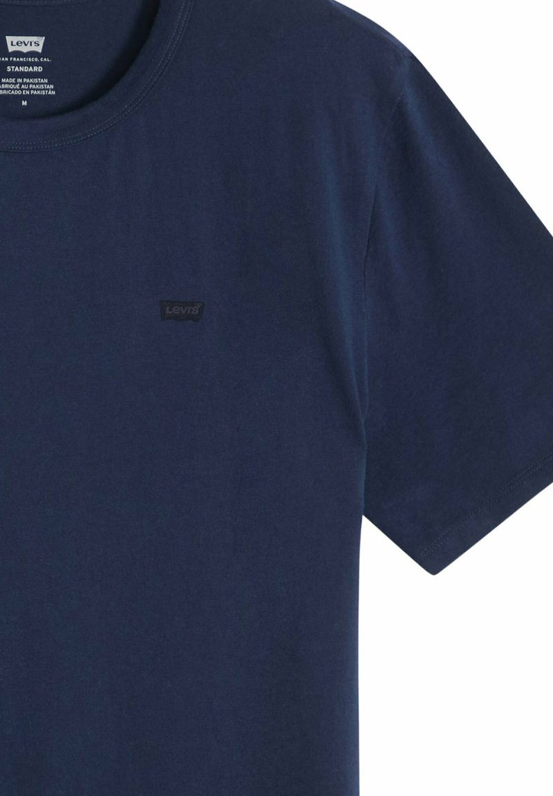 Camiseta de algodón Levi's de manga corta en azul marino con cuello redondo y pequeño parche con el logo negro de Levi's en el pecho izquierdo. Etiqueta de talla mediana dentro del cuello.