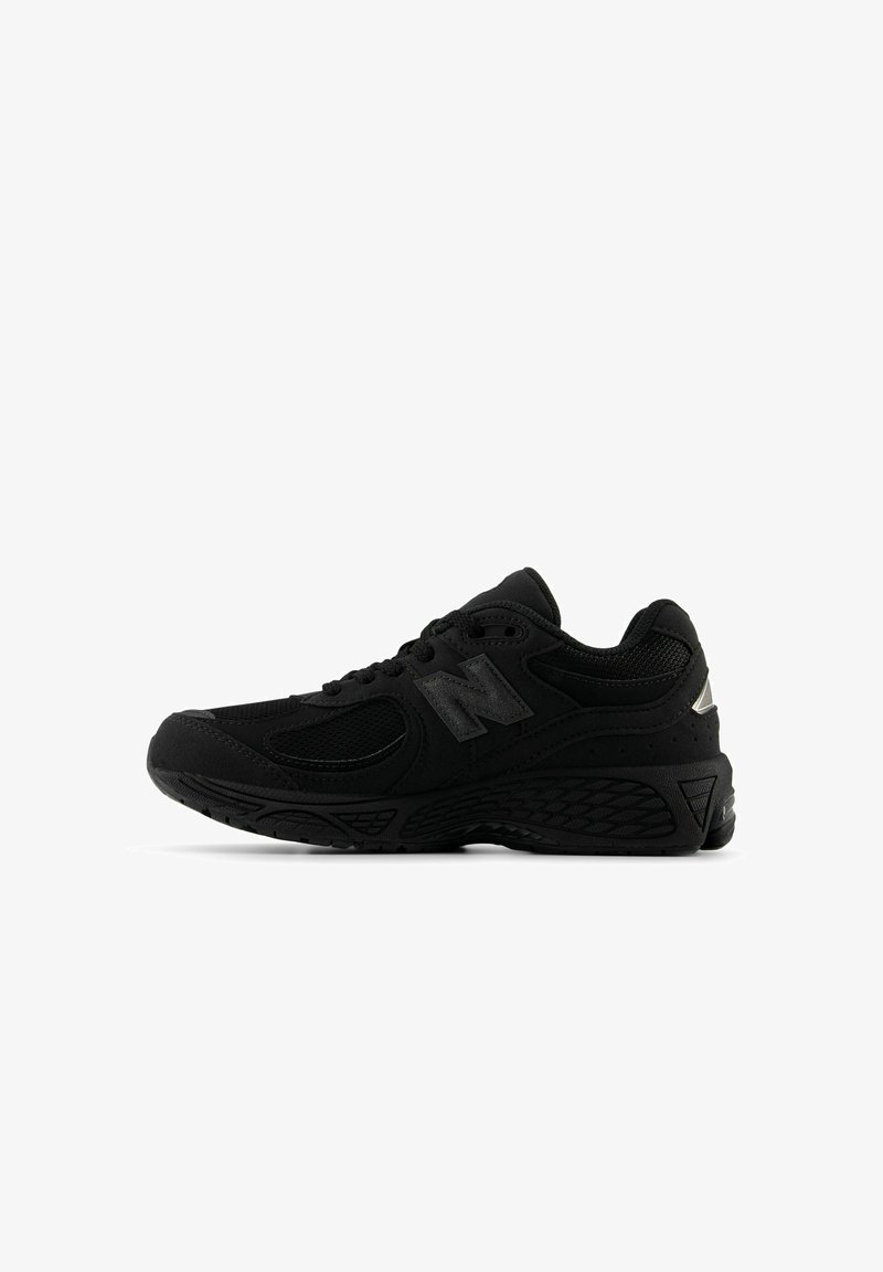 Baskets de sport New Balance noires avec panneaux en mesh, lacets à l'avant, semelle coussinée et logo de la marque sur le côté, vues de profil droit.