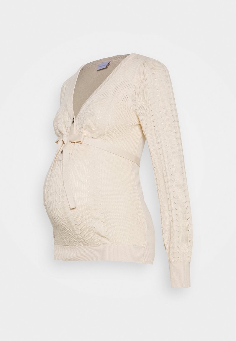 Cardigan de maternité en tricot beige avec un col en V, des manches longues et une ceinture à nouer à la taille. Présente des motifs texturés et une coupe ajustée.