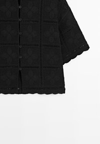 Czarny krótkorękawowy sweterek na szydełku z kwadratowymi motywami kwiatowymi i zapięciem na guziki z przodu.