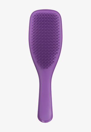 Brosse à cheveux en plastique violet avec des poils courts et flexibles, et un manche lisse et contourné sur un fond blanc.