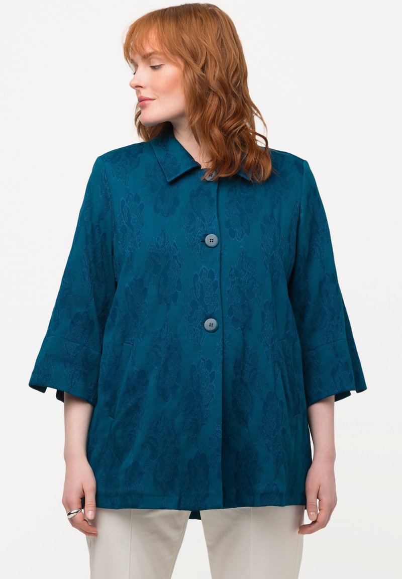 Teal blazer med et blomstrede jacquardmønster, trekvartærmer og knaplukning. Glat tekstur med sidetasker og klassisk krave.