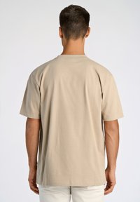 Beige bomulds t-shirt med korte ærmer og rund hals, der har en glat struktur og en lige pasform uden synlig branding eller mønstre.