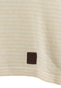 Suéter a rayas de color beige claro que presenta una textura suave y una etiqueta de cuero marrón con el logo "KEY LARGO" en la parte inferior.