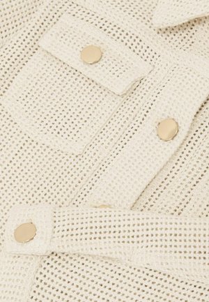 Biela tkaná košeľa s mriežkovým vzorom, vybavená zlatými cvočkami a náprsnom vreckom. Textúrovaná tkanina pridáva rozmer.