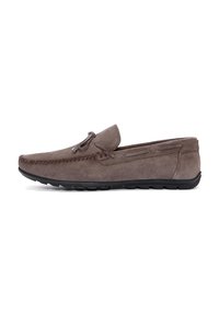Mocasin de ante con punta redondeada, color gris, costura decorativa, acento de cordones en la parte delantera y suela de goma negra flexible.