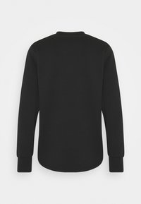 Chemise noire à manches longues vue de dos, avec un col rond et des poignets côtelés.