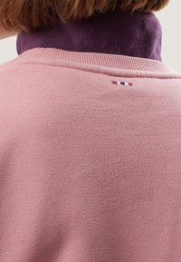 Maglione rosa con una finitura testurizzata, caratterizzato da un colletto viola e un piccolo logo multicolore sulla parte posteriore del collo.