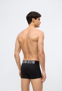 Black boxer briefs with a smooth texture, featuring a contrast logo waistband. The design is fitted, minimalistic with no visible patterns.