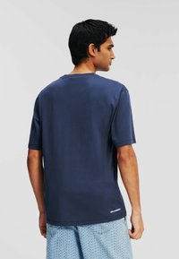 T-shirt à manches courtes bleu marine en coton, doté d'un col rond et d'un logo près de l'ourlet. Texture lisse et coupe décontractée.