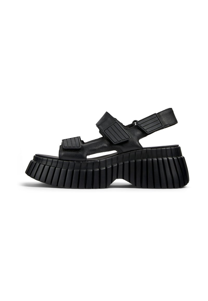 Black platform sandals featuring a chunky, ribbed sole, cut-out sections, and adjustable straps with textured accents for a secure fit.