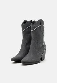 Botas de tobillo de mezclilla gris con puntas en forma de punta, tacones en cuña, bordes deshilachados y cremalleras laterales. Tejido texturizado con un brillo sutil.