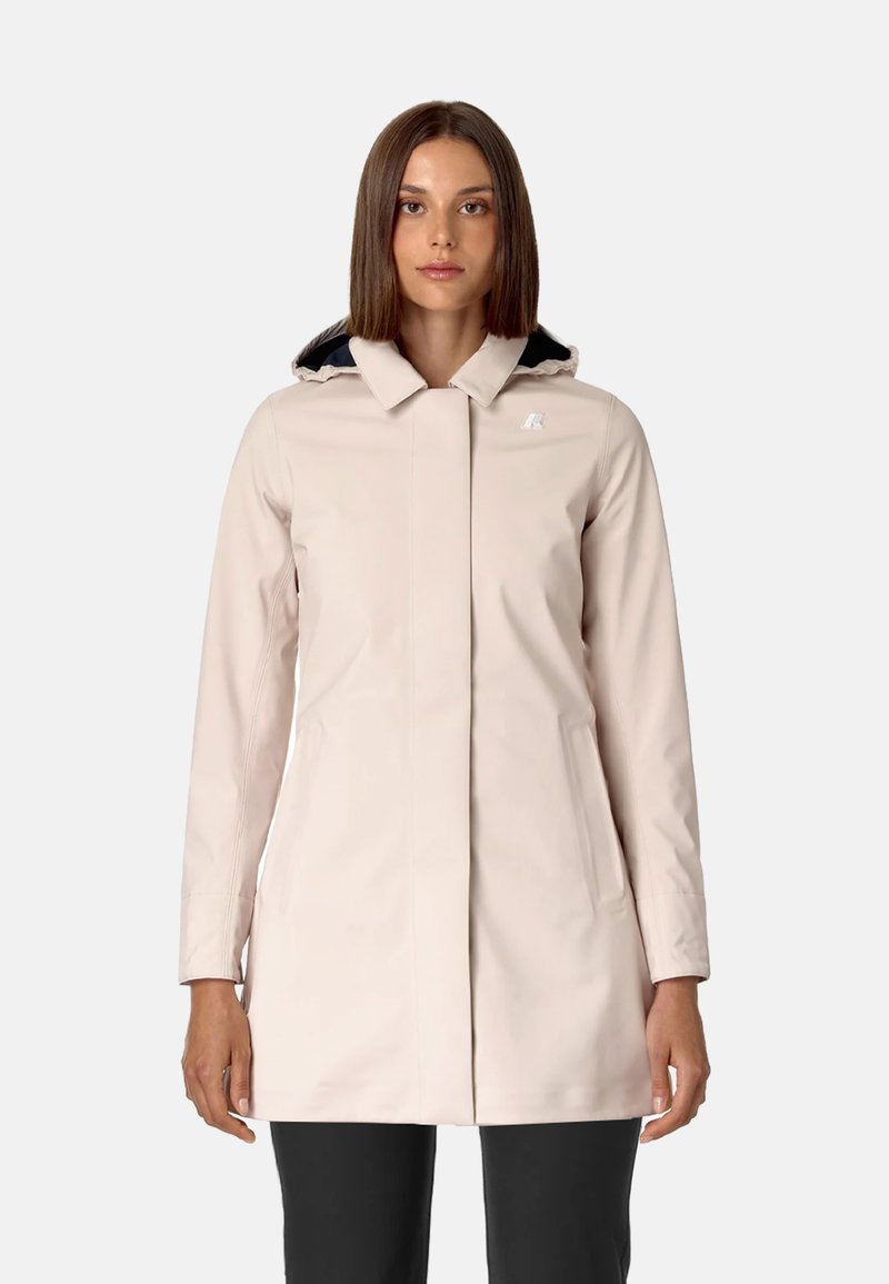 Cappotto impermeabile beige chiaro con colletto alto, chiusura frontale a zip e due tasche laterali. Presenta un cappuccio foderato in blu navy. Tessuto liscio.