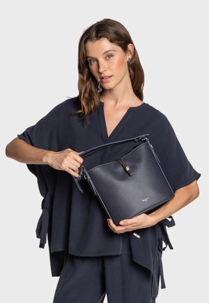 Marineblå læderhåndtaske med struktureret finish, top håndtag og aftagelig skulderrem. Har lynlås lukning og diskret logo detaljer.
