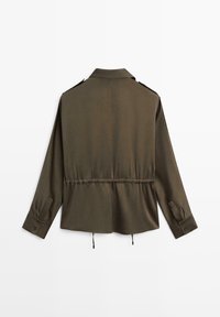 Veste olive verte avec une taille cintrée, des manches longues, des poignets à boutons et un col. Fabriquée en tissu doux avec des détails de design minimalistes.