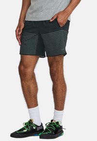 Mannen shorts in donkergroen met horizontale witte strepen, middellange stijl, zijzakken, gecombineerd met kleurrijke sneakers en witte sokken.