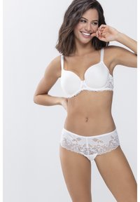 Weißer Spitzen-BH mit glatten Cups und floralem Spitzenbesatz, kombiniert mit passenden weißen Spitzenunterhosen mit gewelltem Saum und floralem Muster.