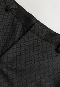 Tessuto nero con una texture che presenta un motivo esagonale. Il design è sottile, con una finitura liscia e una vita pulita.