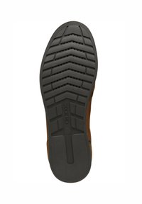 Semelle en cuir brun avec une semelle extérieure en caoutchouc noir texturé, présentant un motif en zigzag et des trous de drainage pour la respirabilité. Logo visible.