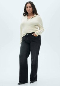 Light beige long-sleeve polo shirt with a collar; black wide-leg jeans with front pockets; pointed black shoes with stud accents.