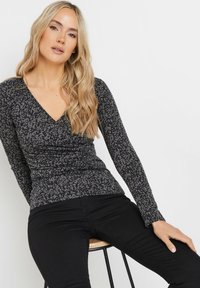 Top a maniche lunghe, scollato a V, in grigio scuro con un leggero motivo astratto. Realizzato in un tessuto morbido, presenta un design aderente e una finitura testurizzata.