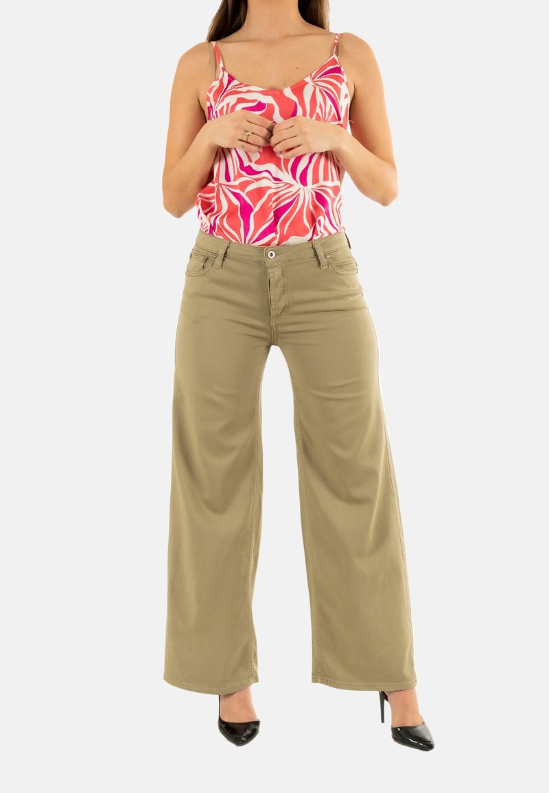 Top sin mangas liviano de color rosa y blanco con un patrón, combinado con pantalones anchos color caqui y tacones altos negros.