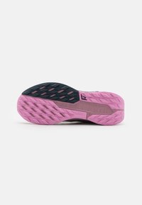La semelle de la chaussure présente un design texturé avec une palette de couleurs noir et rose. Elle comprend des crampons multidirectionnels pour la traction et le soutien.
