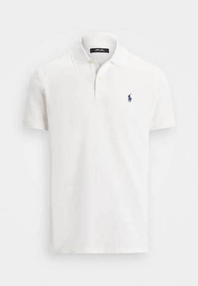 Balts īsām piedurknēm polo krekls ar divām pogām un mazu tumši zilu polo spēlētāja logotipu kreisajā krūtī.