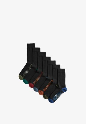 Sette paia di calzini neri con punte e talloni colorati, ciascuno caratterizzato da un motivo a scacchi in vari colori lungo i lati.