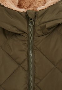 Chaqueta acolchada color verde olivo con cremallera con tirador redondo, forro de piel sintética en la capucha y un exterior suave y brillante.