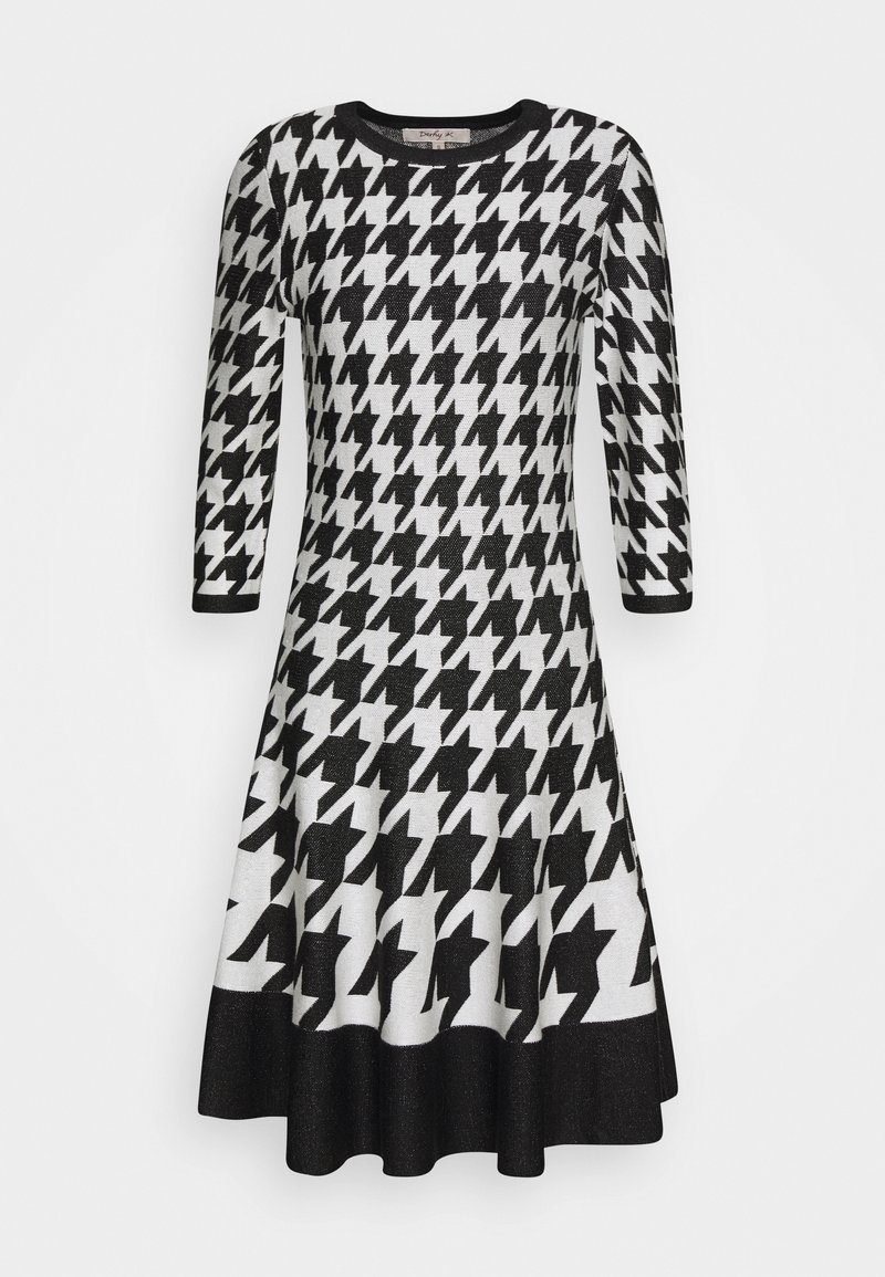 Robe à motif pied-de-poule noir et blanc, manches trois-quarts, jupe évasée avec un ourlet uni noir.