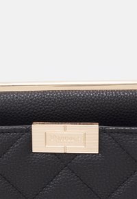 Zwarte gewatteerde leren portemonnee met sluiting van goudkleurig metaal. Kenmerkt zich door een gestructureerd oppervlak en een geperst merklogo. Details met contrasterende stiksels.