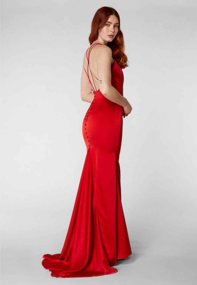 Robe de soirée en satin rouge avec une silhouette ajustée, des bretelles spaghetti et une traîne. Présente des détails de boutons le long du dos pour la fermeture.