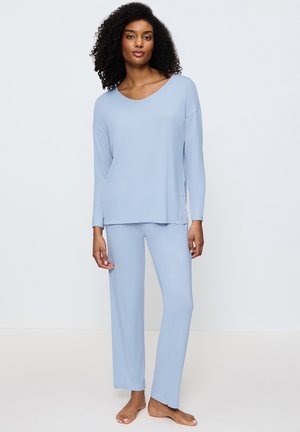 Top azzurro chiaro a maniche lunghe con scollo a barchetta e dettagli in pizzo ai lati, abbinato a pantaloni dritti in morbido tessuto.