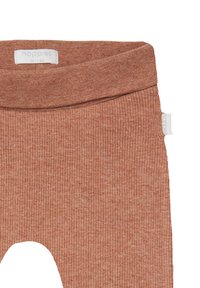 Rostfärgade ribbade leggings med en vikbar elastisk midja och en liten vit etikett på sidan. Mjuk, stretchig tyg.