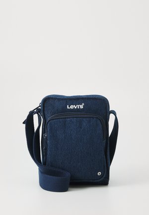 Sac en denim bleu en bandoulière avec une poche frontale zippée, une sangle réglable et le logo Levi's sur le dessus. Texture lisse et forme rectangulaire.