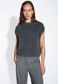Haut en tricot gris, flou, à manches courtes et col rond, associé à un pantalon gris ajusté, avec poches latérales et coupe droite.