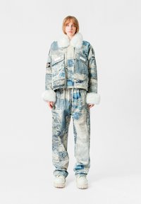 Chaqueta y pantalones de denim con un patrón desgastado en azul y blanco, con un cuello y puños de peluche blanco, en un ajuste relajado.