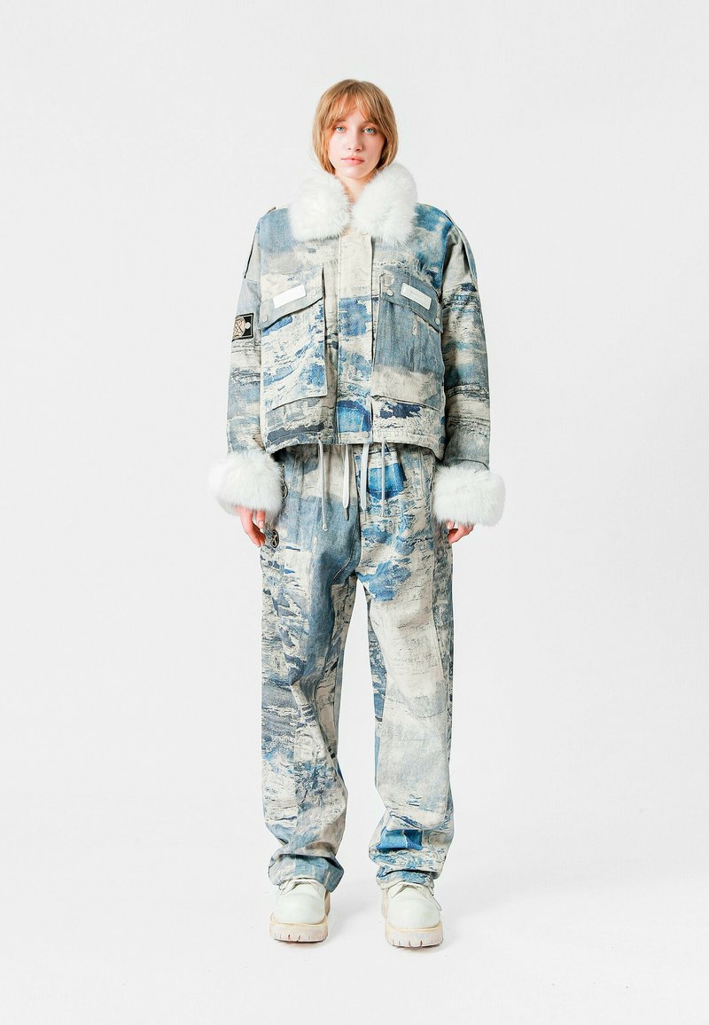 Chaqueta y pantalones de denim con un patrón desgastado en azul y blanco, con un cuello y puños de peluche blanco, en un ajuste relajado.