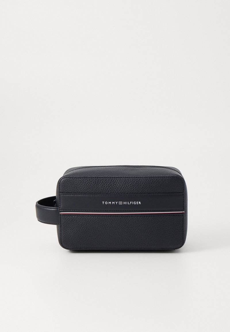 Geantă de toaletă texturată neagră cu închidere cu fermoar, având o mânere mică și o bandă de logo orizontală. Design subțire și dreptunghiular.