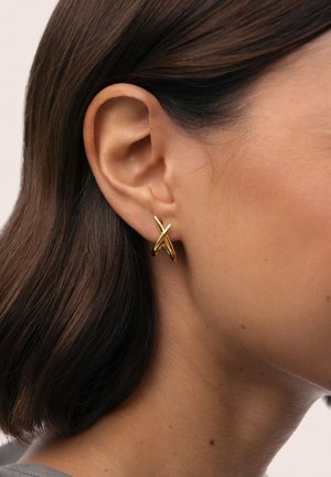 Orecchini color oro con un design astratto e intrecciato, fissati saldamente, esposti su uno sfondo neutro.