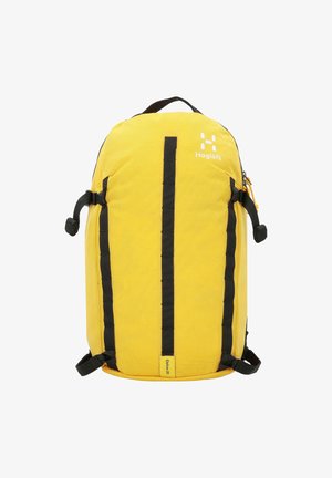 Zaino giallo con spallacci neri, caratterizzato da una forma arrotondata, tessuto testurizzato, maniglia superiore e una tasca con zip laterale. Logo del marchio visibile.