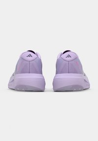 Para jasnofioletowych butów do biegania Adidas widziana od tyłu, z logo marki na pasku pięty i grubymi, amortyzującymi podeszwami.