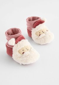Jultema babystrumpor i röd och vit, med ett plyschansikte, randiga muddar och en mjuk, strukturerad ovandel.