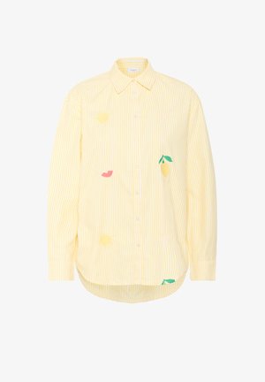 Sárga csíkos gombos ing, amely citrom, ajkak és nap motívumokkal hímzett. Az anyag könnyűnek és lélegzőnek tűnik.