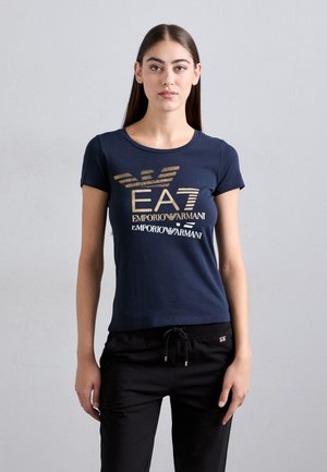 Marineblauw T-shirt met korte mouwen met een gouden logo-opdruk. Zachte stof, aansluitend ontwerp met ronde halslijn, gecombineerd met zwarte broek met trekkoord.