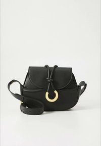 Schwarze Lederhandtasche mit rundem goldfarbenem Akzent, geschwungener Klappe, verstellbarem Schultergurt und glatter Textur. Kompaktes, strukturiertes Design.