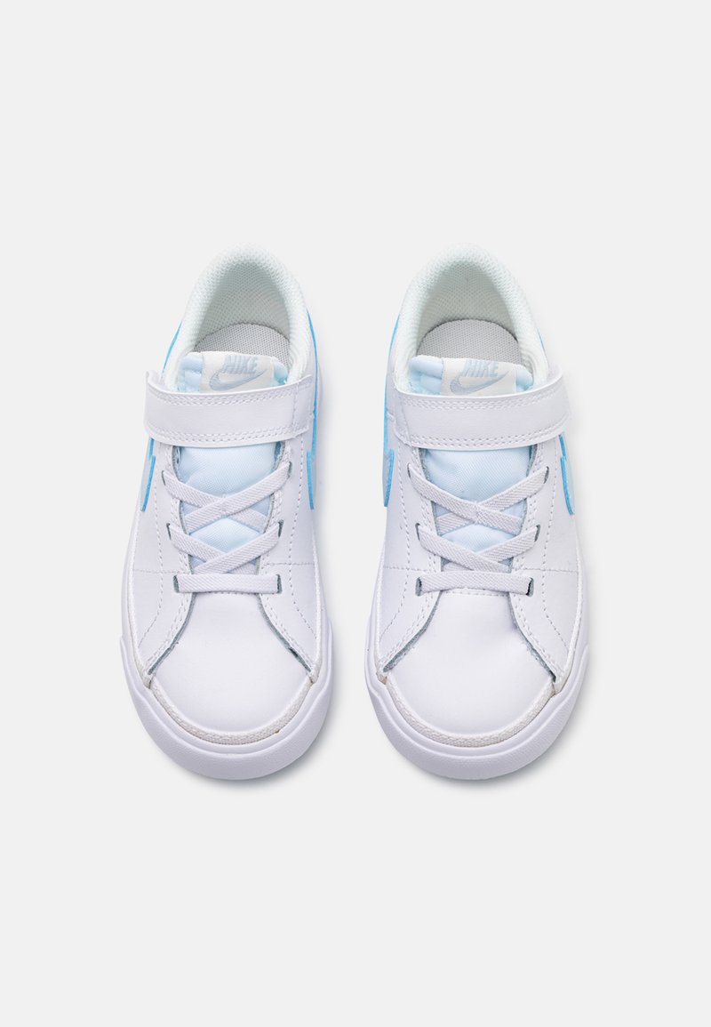 Zapatillas Nike blancas con detalles en azul claro, con una parte superior sintética lisa, cierre con cordones y una correa para un ajuste seguro. Diseño de punta redondeada.