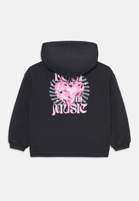 Schwarzer Hoodie mit einem Frontgrafik, die ein pinkes Herz aus reflektierenden Pailletten zeigt und den Text "VERLOREN IN DER MUSIK" in fetter Typografie.